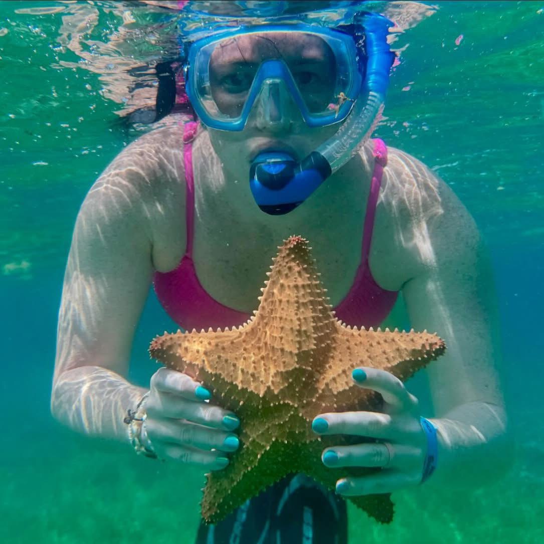 Hannah snorkeling and holding a starfish underwater